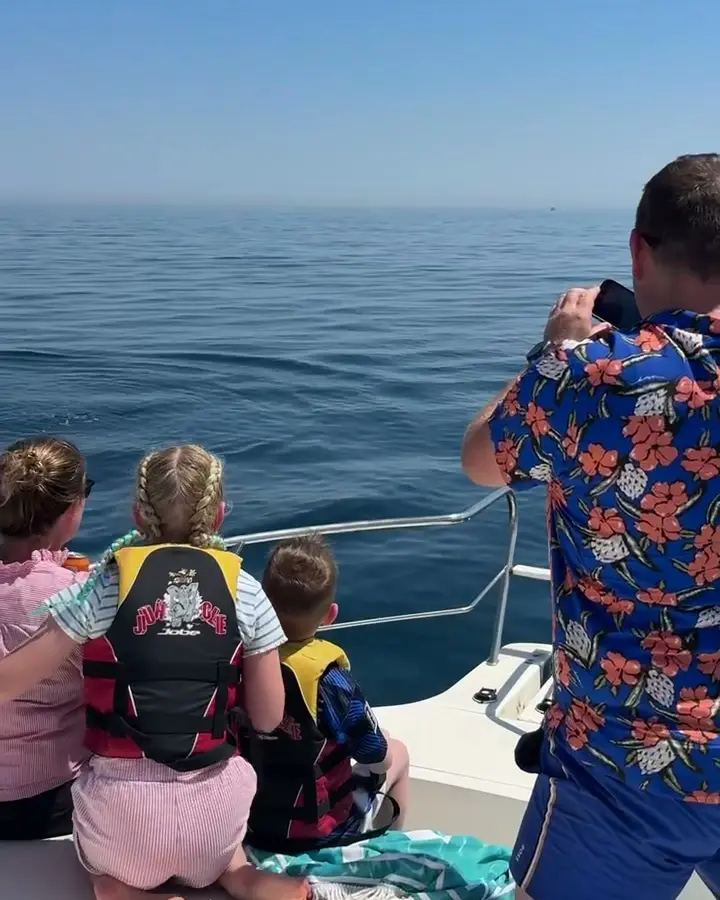Familia mirando delfines desde la popa del Perla Fisher
