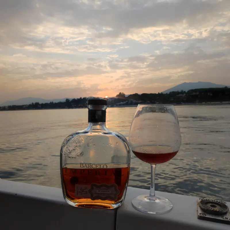 Copa de vino al atardecer a bordo, con la costa de Marbella